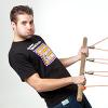 A man in black pulling on a wooden pole that has a series of ropes and pullies attached.