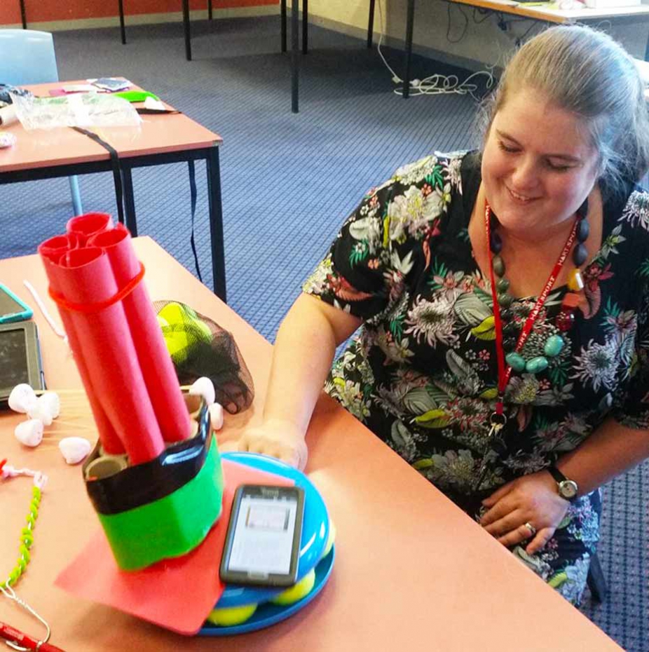 Questacon Smart Skills Teacher Workshop teacher measures vibration in a shaking structure made of cardboard with a smart phone.