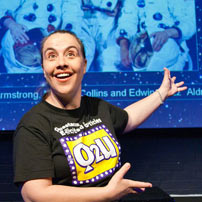 a woman smiling and pointing to a screen behind her