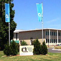 A sign with Questacon technology learning centre. 60 Denison street printed on it. A large building is in the background