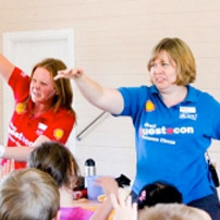 Two woman standing in front of a group of young school students.