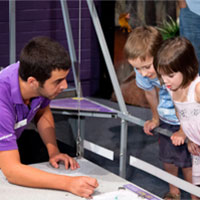 a young man shows two young children a science experiment