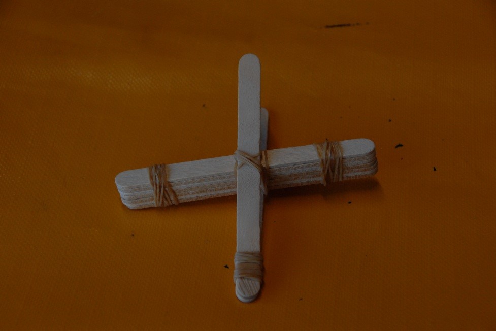 Marshmallow catapult An image showing seven icy pole sticks wedged between two icy pole sticks secured with rubber bands