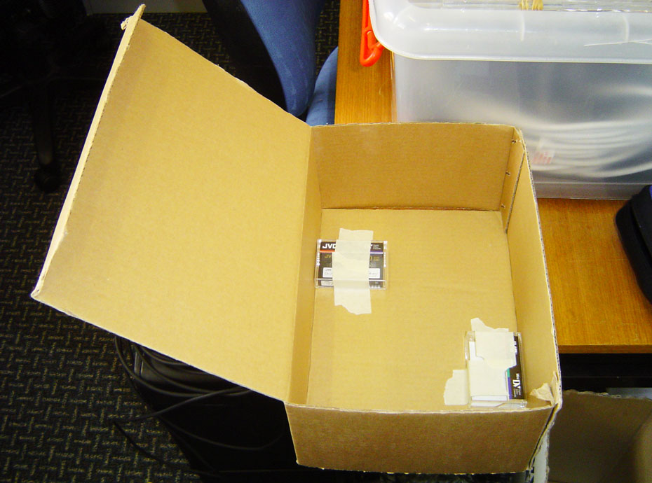 The position of the blocks can be found by using senses other than our sight. A open cardboard box with two cassette tapes taped with masking tape to the bottom of the box.