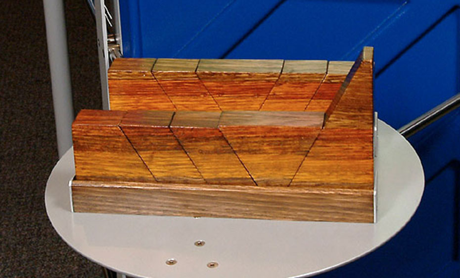 Push the blocks towards each other. Watch what happens to the blocks, which represent tectonic plates or the Earth’s crust. A blue, green and grey exhibit stand with a large piece of timber at the front with slots cut into it.