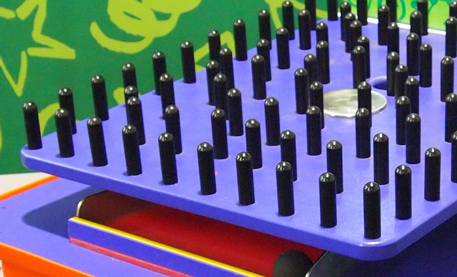 Mazes require planning ahead on a route or pathway to reach the end. A purple square platfrom wtih black pegs facing up.
