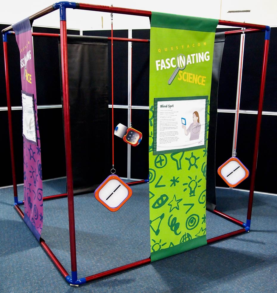 Different hemisphere of the brain controls your sense of rhythm and melody. A large blue and red cube frame that has purple and green information banners hanging between top and bottom bars of the cube. There are also square orange and white shapes hanging from the frame.