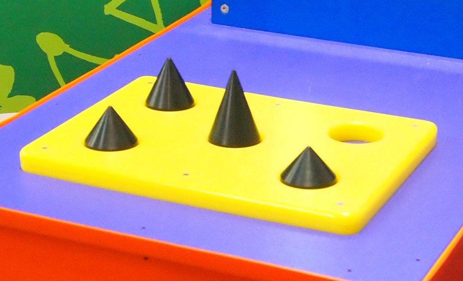 Try to lift three cones which are the same mass, but are shaped differently and are difficult to pick up because friction doesn't allow adequate grip. A yellow flat board, with four black cones pointing upwards.