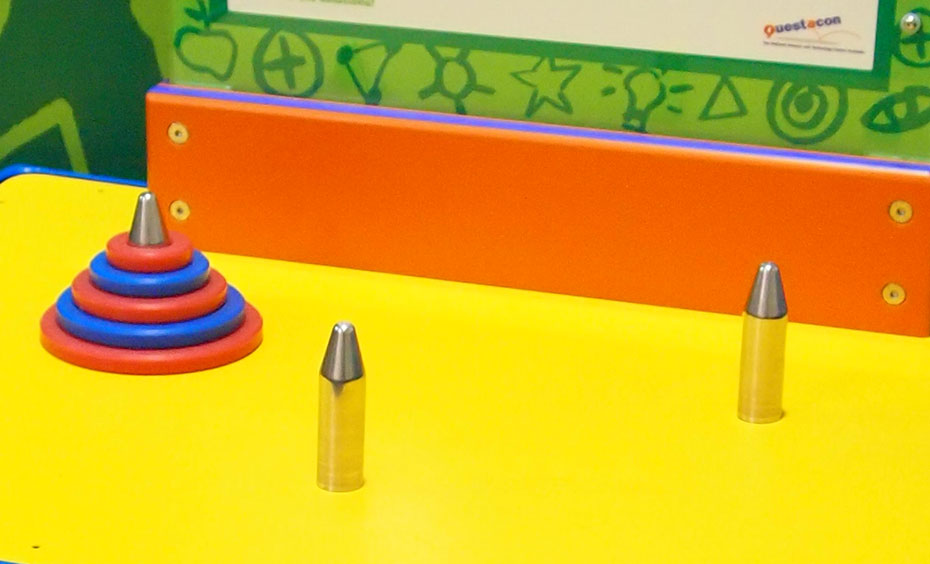 Move all discs from one peg to another peg, using certain rules and within a minimum number of moves. A yellow surface with 3 chrome pegs of which one has five red and blue discs threaded onto it from largest to smallest disc.