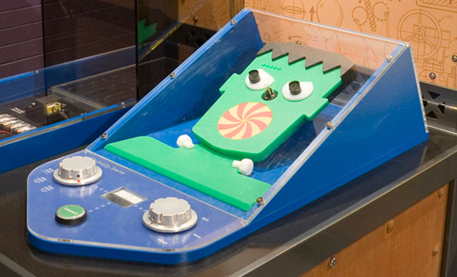 Use different generators (batteries, power pack, solar cell or hand crank) to animate a cartoon face. A timber and steel exhibit table with matching information panel at the back. On the table are two blue interactive objects, of which one has a green cut out face.
