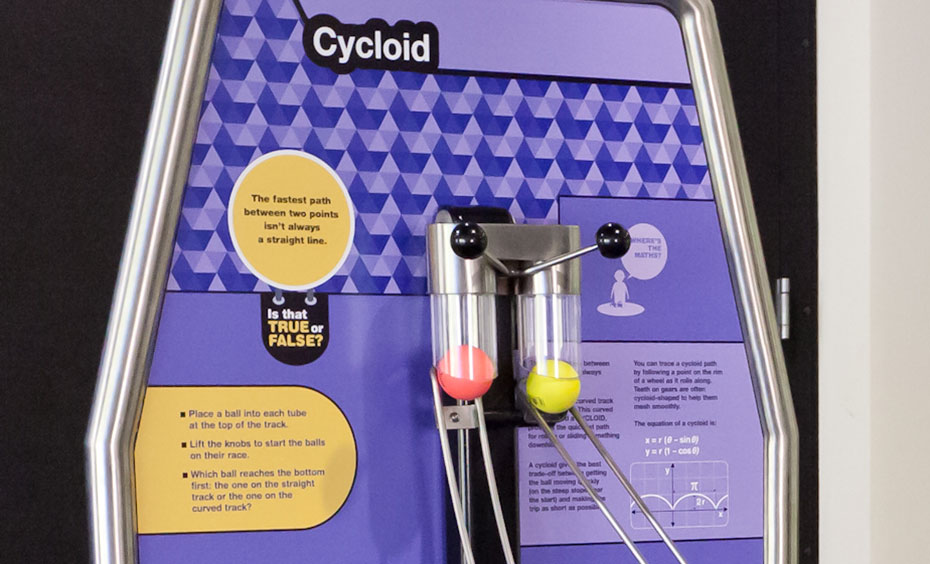 The fastest path between two points isn’t always a straight line. A vertical purple information panel, with two clear tubes that contain a red and yellow ball.