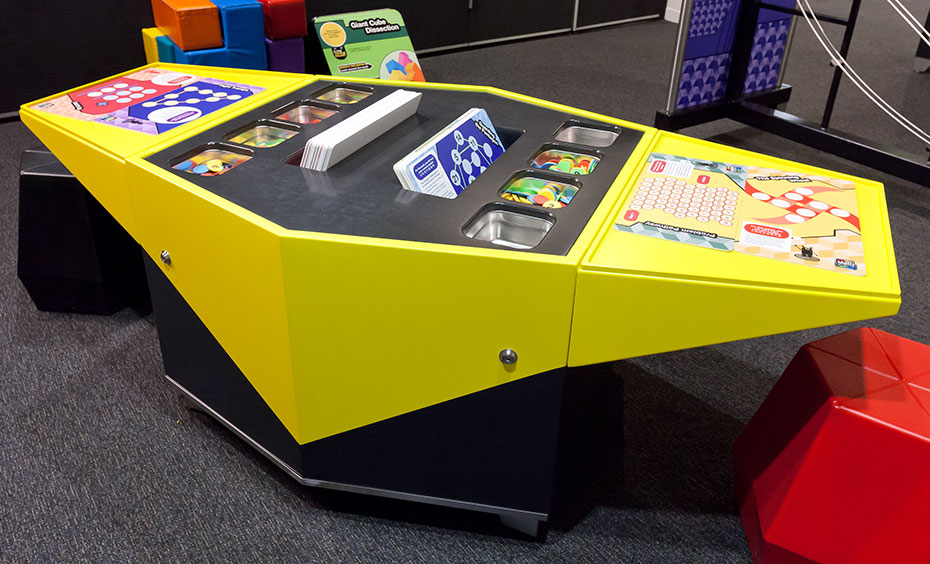 The puzzles cover a wide variety of topics. A yellow and black table with puzzle cards and discs in the centre.