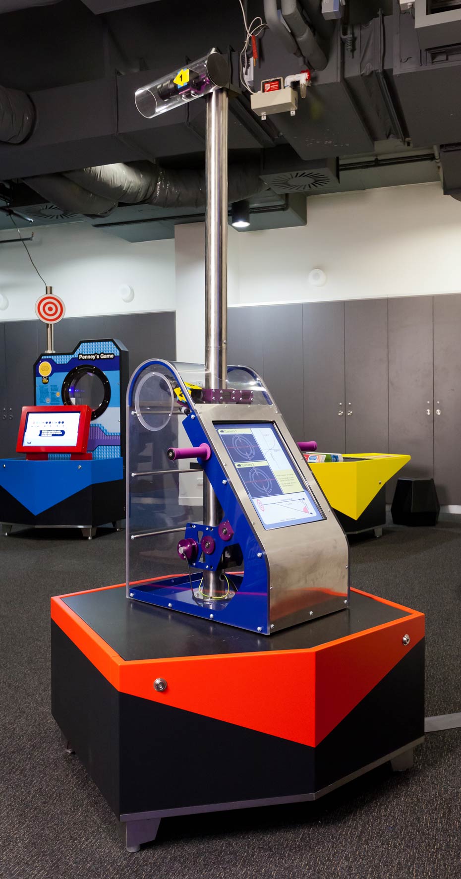 As you use the exhibit, what do you notice on the graph showing tan θ and the distance to the target? An exhibit table supporting a steel mechanical device that has a tall pole and camera coming out of the top.
