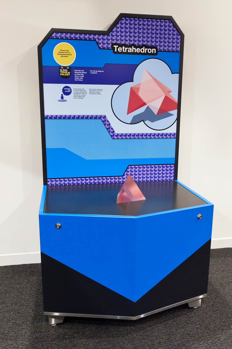 What does the final tetrahedron shape remind you of? A pink pyramid in two halves sitting on a black and blue exhbition table.