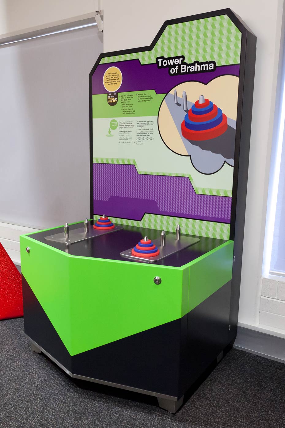 The minimum number of moves required to solve a Tower of Brahma puzzle depends on the number of discs being used. A black, green, white and purple exhibit table with matching information panel.