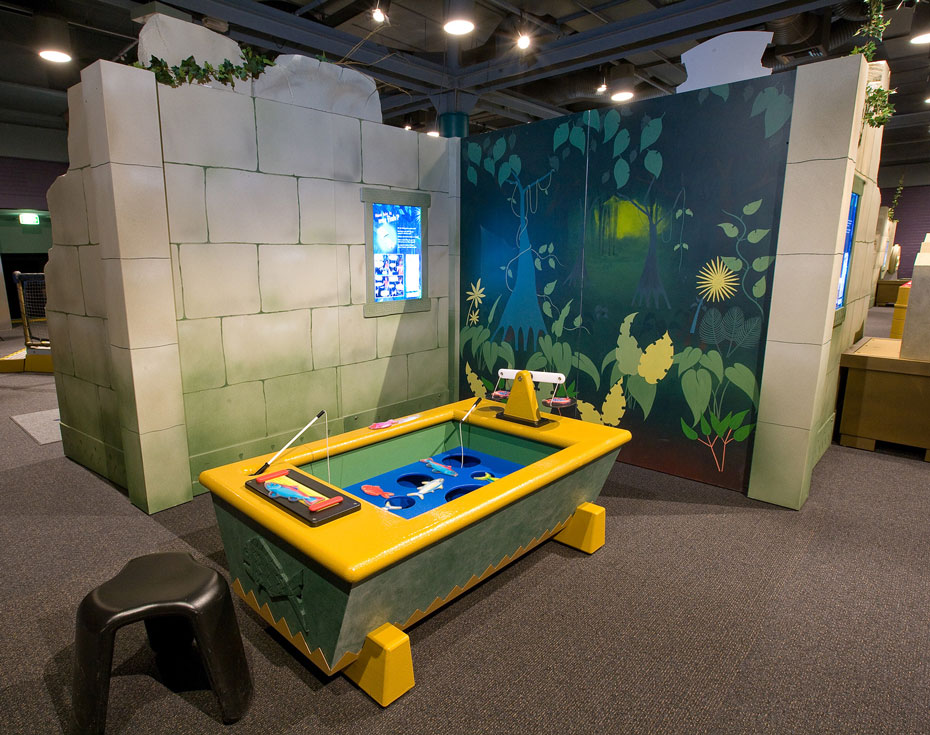 Objects such as a fish can be measured in different ways. A yellow and blue tub with cut out fish and small fishing poles sits in front of a fake stone wall and jungle scene.