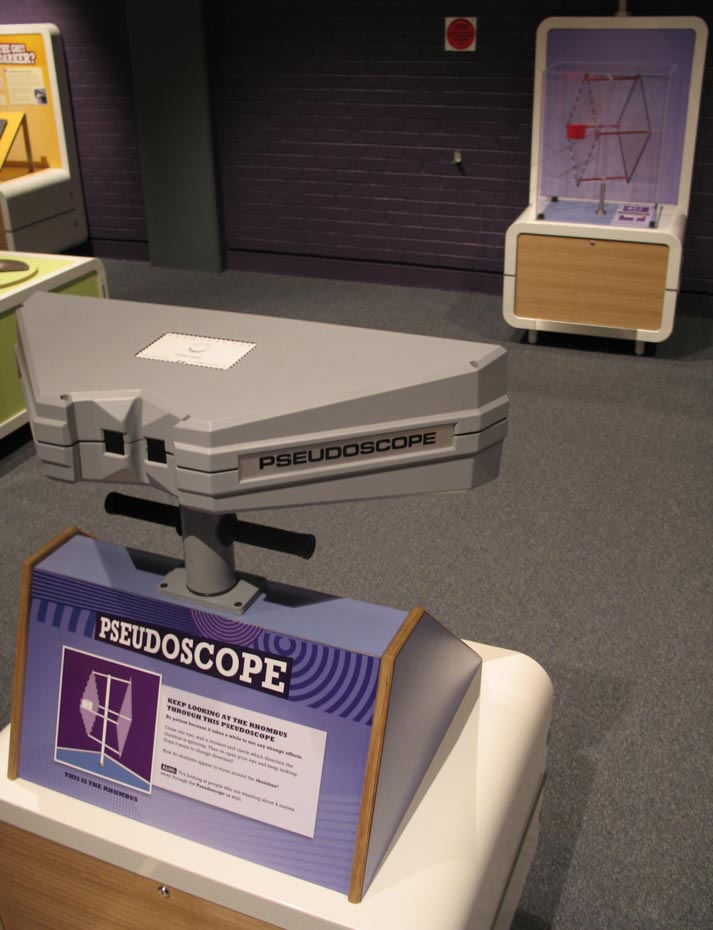 Do people and things appear strange through each 'scope? Two purple and cream exhibits about 5 metres apart. The text 'Pseudoscope' is on the nearest exhibit.