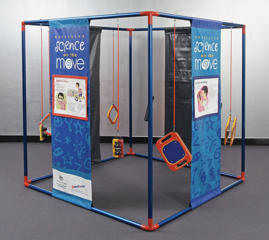 Look into the tube and study the patterns inside. A large red and blue cube frame that has blue and orange banners running from top to bottom with different information on each. There are orange and yellow objects hanging from the frame.