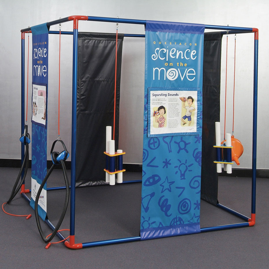 Place different tubes against the ear to notice low and high pitched ambient sounds. a blue, black and white cube structure that has vinyl blue and white information panels from top to bottom with spaces in between. There are also different sound exibits hanging from orange cord from the cube structure.