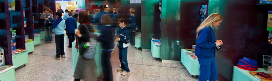 Parents and school students looking at display cases of shop merchandise. A time effect blur has been used on moving people in the photograph.