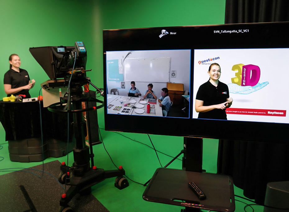 A presenter stands infront of camera presenting to a class of students