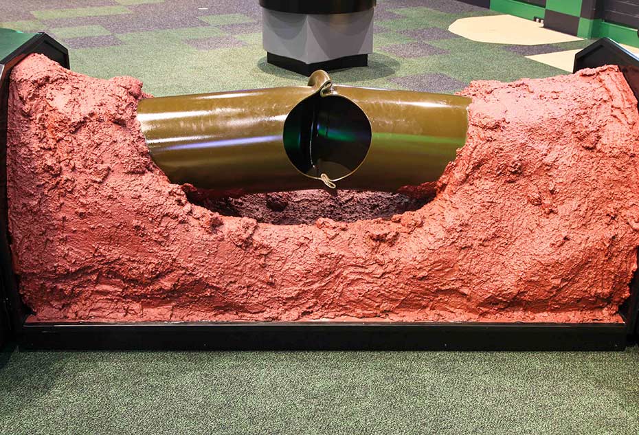 A section of damaged gas pipe shows the strength of a 6.6 magnitude earthquake. a steel pipe bent and with a large whole in the side of the pipe.