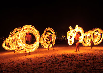 People on a beach twirling fire