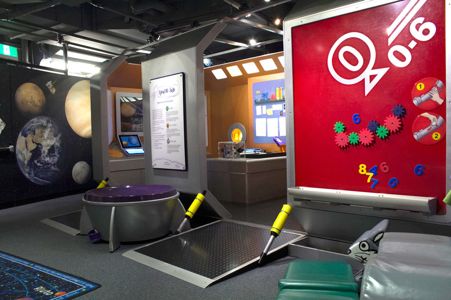 A walk in 'space ship' allows children to role play being an astronaut, while also offering simple hands-on science experiments that they might do 'mid-flight'. A large red magnetic sign holding colourful magnets in the shape of cogs and numbers, a wall painted with planets and the entrance way to a pretend space ship