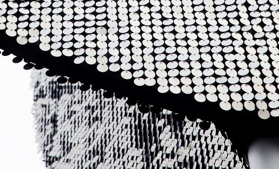 Spin the wheel to orient the flicker discs according to changes in wind direction. A close up of hundres of circular metal silver discs.
