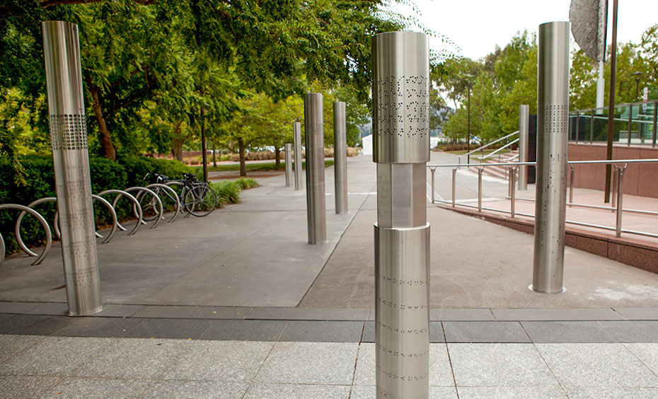 Eight stainless stell pillars are covered in letters, numbers or symbols, creating eight encrypted messages for you to decipher. Eight stainless steel vertical poles about 2 metres in height are spaced apart and embedded into a concrete and paved garden area. On each of the poles are laser cut out cryptographic symbols.