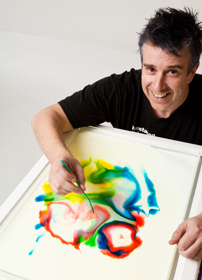 A man painting colour patterns on a flat surface.