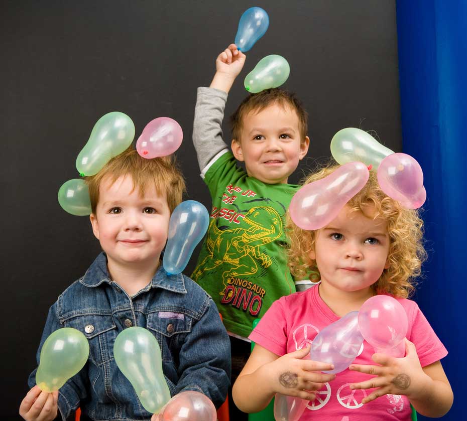 A young boys with balloons clinging to his hair.