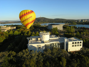a hot air ballon over a large building surround by trees