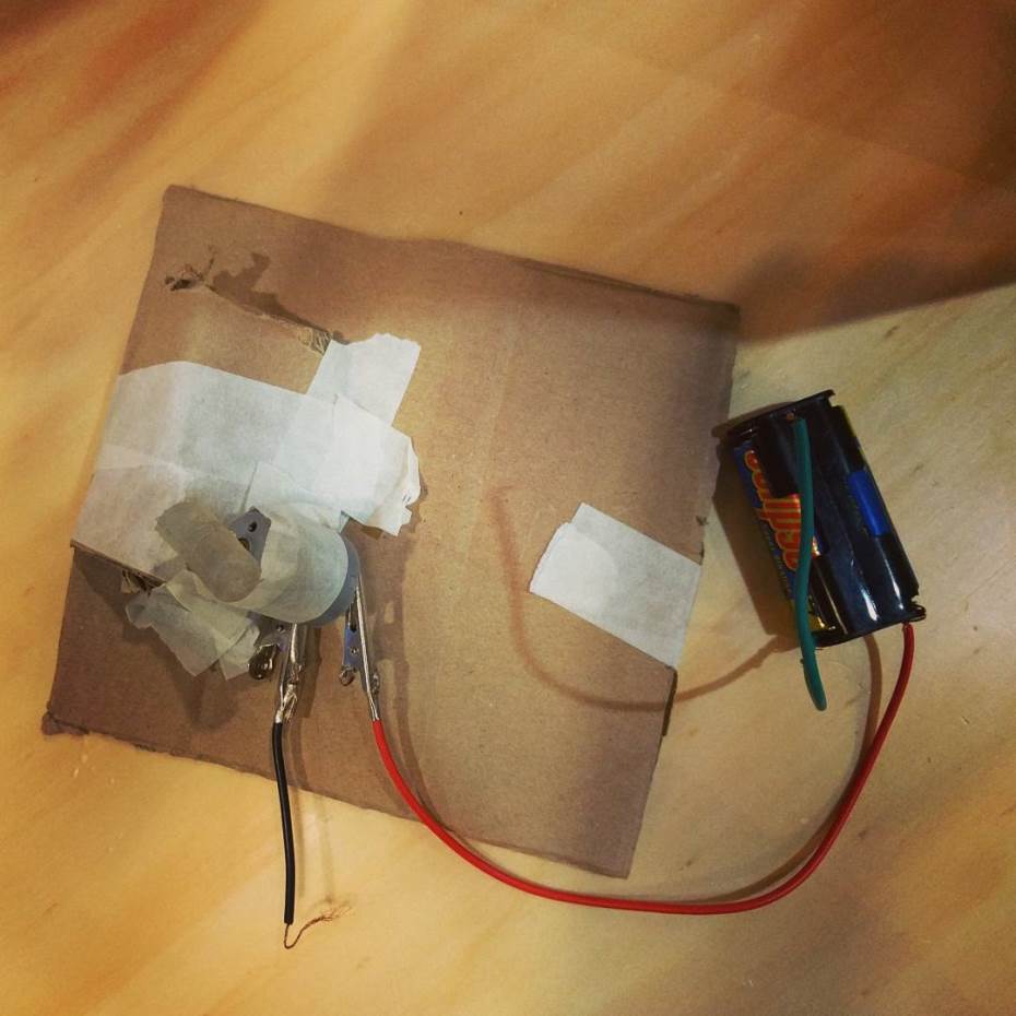 A circuit of a motor and battery taped onto a piece of cardboard