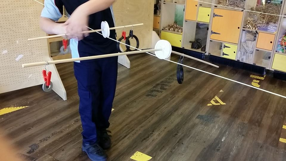 A visitor tinkers with their sculpture to improve how it balances on a zip line