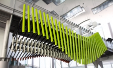 Green steel verticle poles attached in a wave configuration, in a white large room