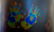 Colourful blue, yellow and red handprints on a black background.