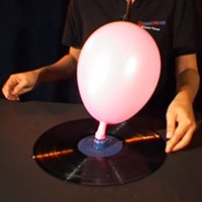 A balloon attached to an old record sitting on a table.