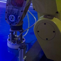 a yellow robot arm with a hocky puck attached at the end of it's arm sitting on a blue air hockey table
