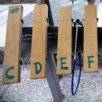 Four limestone blocks layout as a keyboard on a metal stand, with one blue plastic and metal mallets attached. 