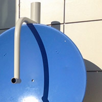 A large blue concave vertical dish sits in the corner with a large window to the left and a white wall to the right.