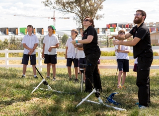 presenters launching paper rockets while students look on