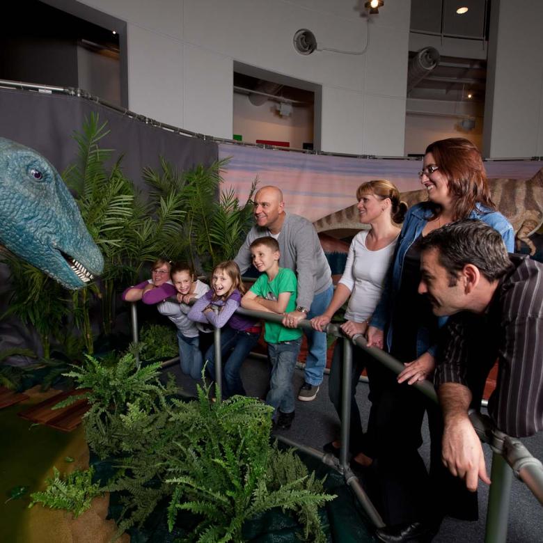 People stand and stare at an animatronic dinosaur