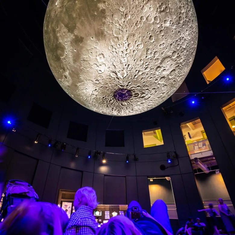 People lay underneath a model of the Moon