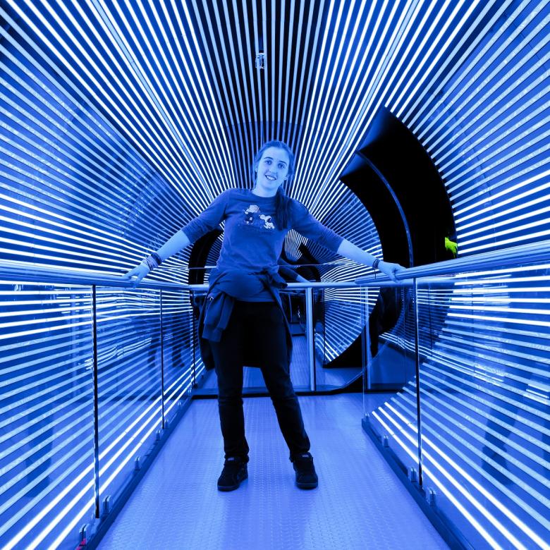 A child stands in a tunnel with lines of light running along the sides