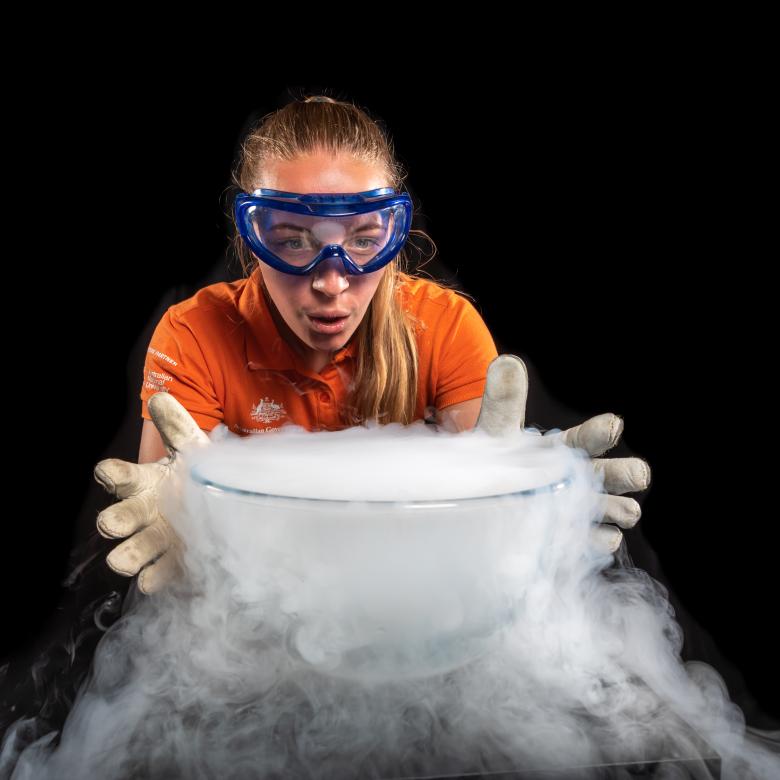 A Questacon Science Circus presenter standing behind a bowl of water boiling liquid nitrogen