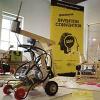 A robot in front of an Invention Convention Banner