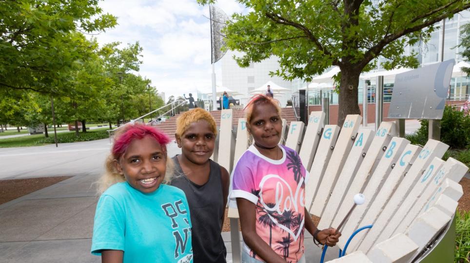 Indigenous children using the xylophone exhibit outside Questacon
