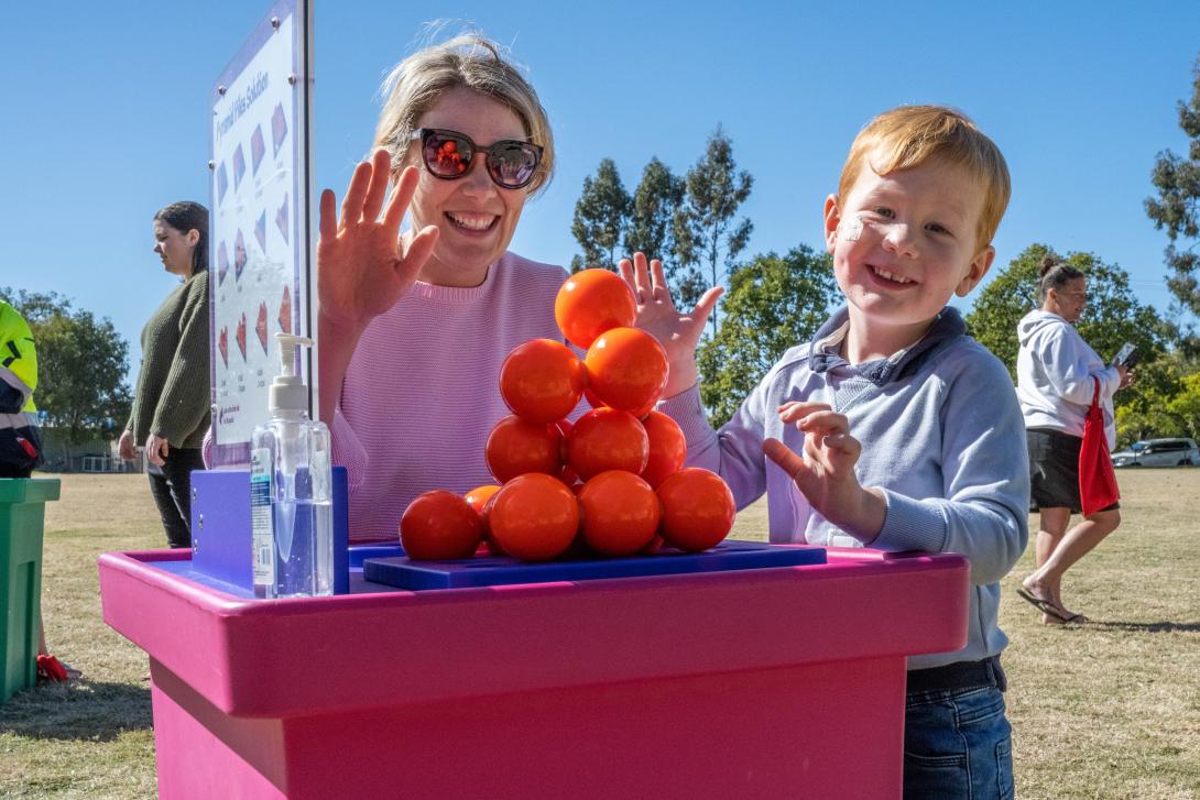 A parent and child stand by a pile of balls